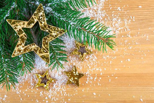 Golden Christmas stars with pine branch and snow on wooden background