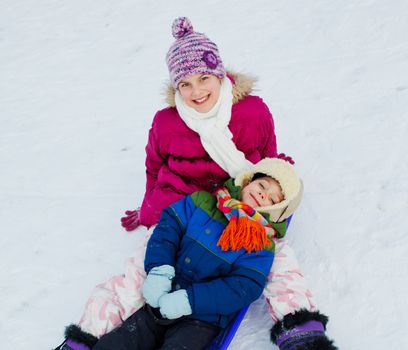 Two happy kids is sledging in winter-landscape