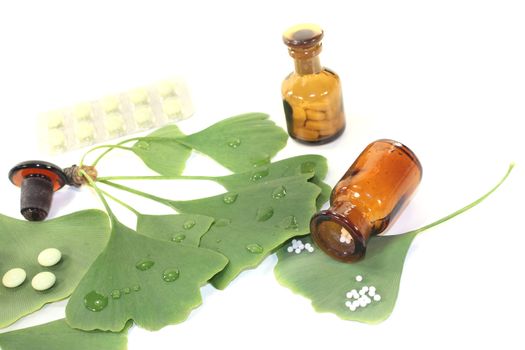 Ginkgo leaf with pills and pharmacist bottle on bright background