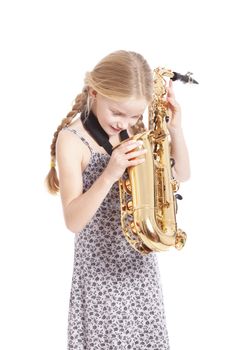 young girl in dress looking into saxophone against white background