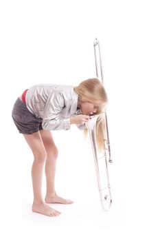 young girl looking into trombone in studio against white background