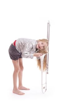 young girl in silver jacket having fun with trombone in studio against white background