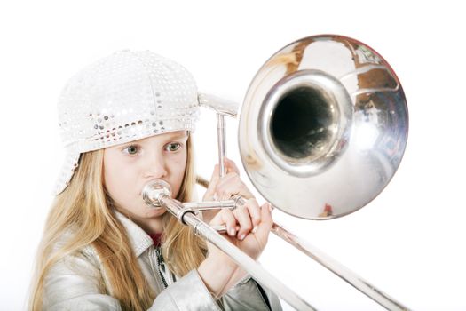 young girl with cap playing trombone in studio against white background