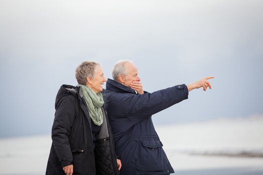 mature happy couple walking on beach in autumn lifestyle healthy