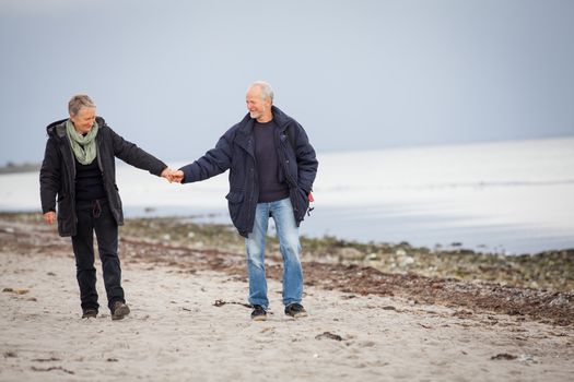 mature happy couple walking on beach in autumn lifestyle healthy