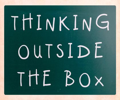 Thinking outside the box phrase, handwritten with white chalk on a blackboard