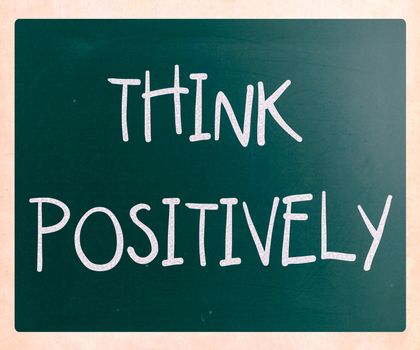 "Think Positively" handwritten with white chalk on a blackboard