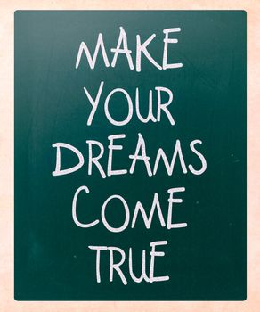 "Make your dreams come true" handwritten with white chalk on a blackboard