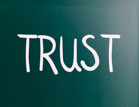 The word "Trust" handwritten with white chalk on a blackboard