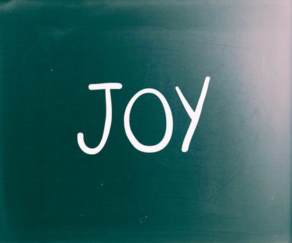 The word "Joy" handwritten with white chalk on a blackboard