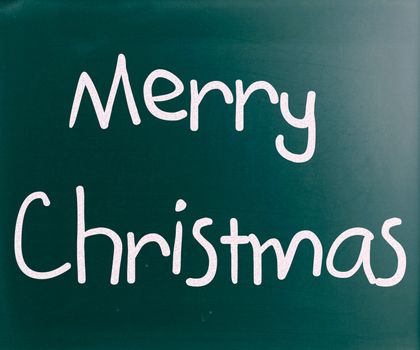 "Merry Christmas" handwritten with white chalk on a blackboard