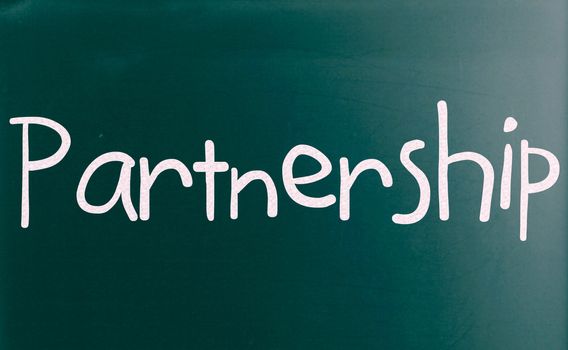 The word "Partnership" handwritten with white chalk on a blackboard