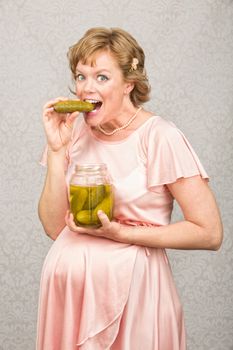 Happy pregnant person eating from a jar of pickles