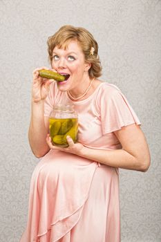 Overjoyed pregnant female eating from a jar of pickles