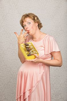 Single pregnant woman with candy licking her fingers