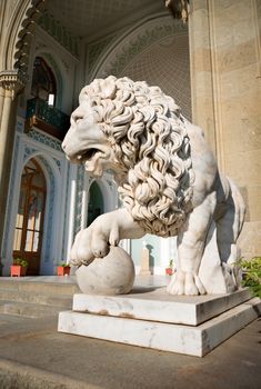 Sculpture of lion with a ball on a background of palace