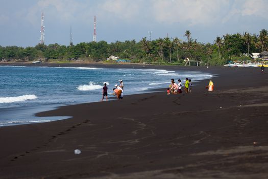 BALI, INDONESIA - SEP 26: Balinese Hindu devotees give offerings for the spirits of the the sea an a beach for the ritual near Goa Lawah Bat Cave temple on Sep 26, 2012 in Bali, Indonesia. 