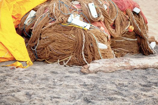 Generic horizontal color capture of a fish farming nets wrapped and stored overnight under a yellow tarpaulin on the sands at  Manaputta Beach, Pondicherry, Tamil Nadu, India