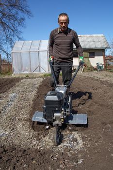 Middle aged man working in the garden with Garden Tiller