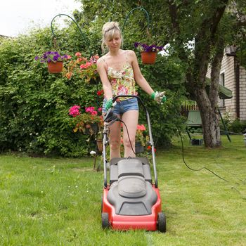 Woman mowed grass in a flower garden