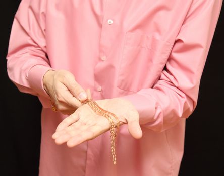 man holds in hand a gold chain