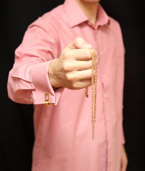 man holds in hand a gold chain