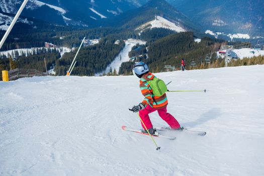 Girl on skis in soft snow on a sunny day in the mountains