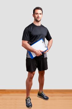 Personal Trainer, with a pad in his hand, in a gym