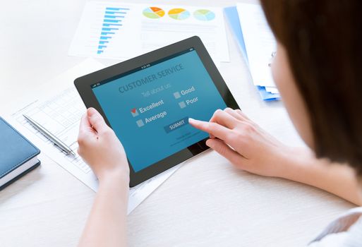 Businesswoman holding modern digital tablet with customer service survey form on a screen. Red tick on excellent choice showing customer satisfaction