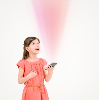 Inspired cute little girl in red dress looking up on ray of light from mobile phone in her hand. Isolated on beige background.