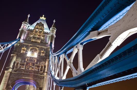 Looking up at the impressive architecture of Tower Bridge at night.