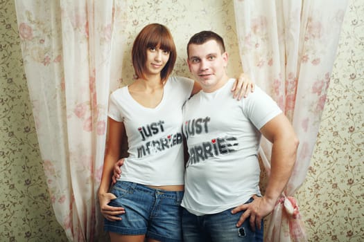 Happy newlyweds hugging T-shirts, shot in the studio