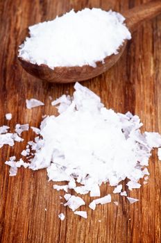 Heap and Wooden Spoon of White Crystal Salt on Wooden background 