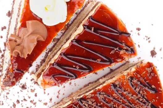Three Slices of Delicious Cake with Glazed Cream and Grated Chocolate closeup on white background. Top View