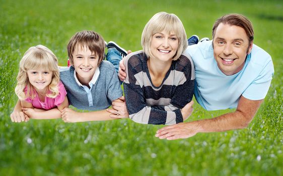 Smiling family of four lying in their backyard