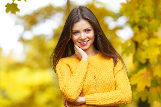 Portrait of a beautiful young woman over autumn tree background