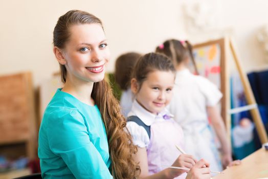 children draw with the teacher in the classroom drawing