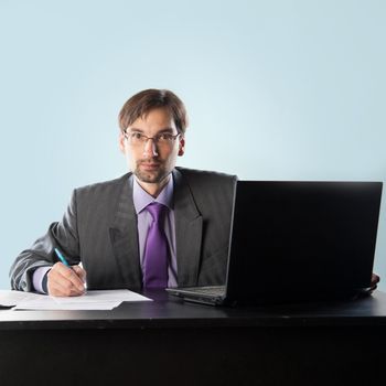 businessman at his desk with a laptop and papers