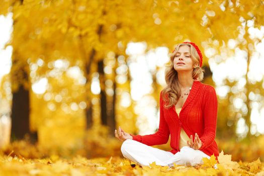 Yoga woman sitting in lotus position in autumn park