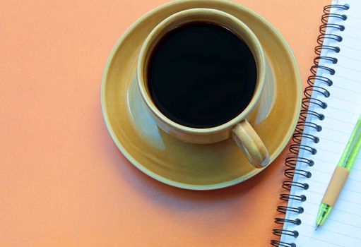 Coffee cup and pen on a red background.