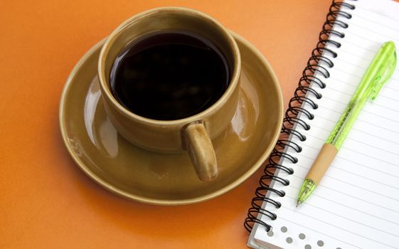 Coffee cup and pen on a red background.