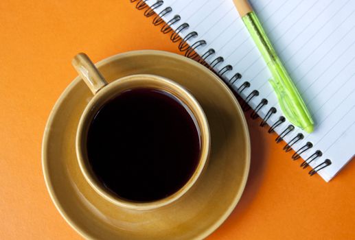 Coffee cup and pen on a red background.