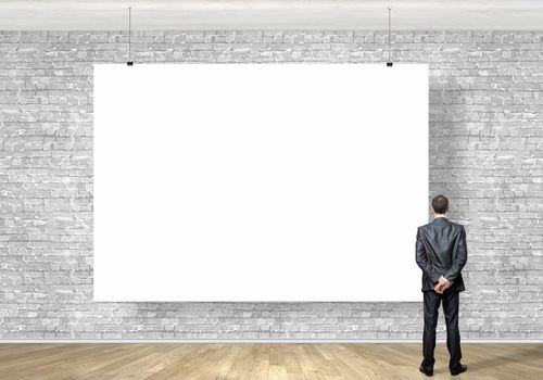 Image of businessman standing with back and looking at white banner