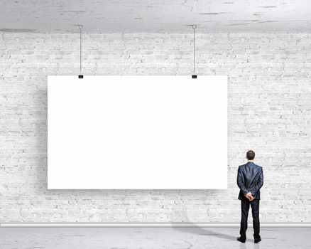 Image of businessman standing with back and looking at white banner