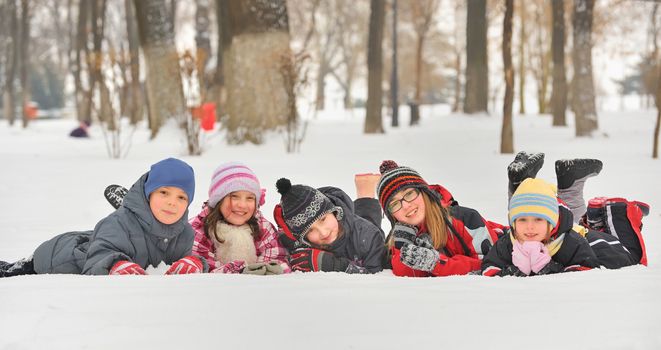 Group of children playing on snow in winter time