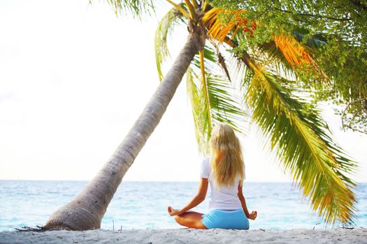 yoga woman on sea coast under palm