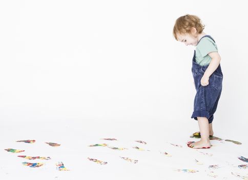 girl making colored footprints on the floor. studio shot with light grey background