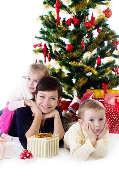 Happy mother with two children under Christmas tree with presents
