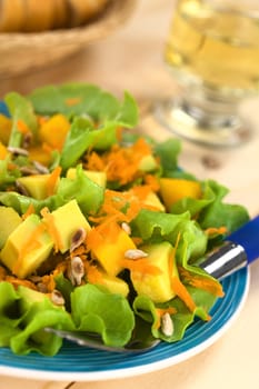 Fresh and light vegetarian salad amde of mango, avocado, grated carrots and lettuce, sprinkled with roasted sunflower seeds (Selective Focus, Focus one third into the salad)  
