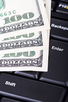 One hundred dollar banknotes on black computer keyboard.